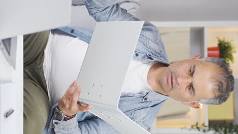 Vertical-video-of-Man-working-on-laptop-throws-files-angrily.